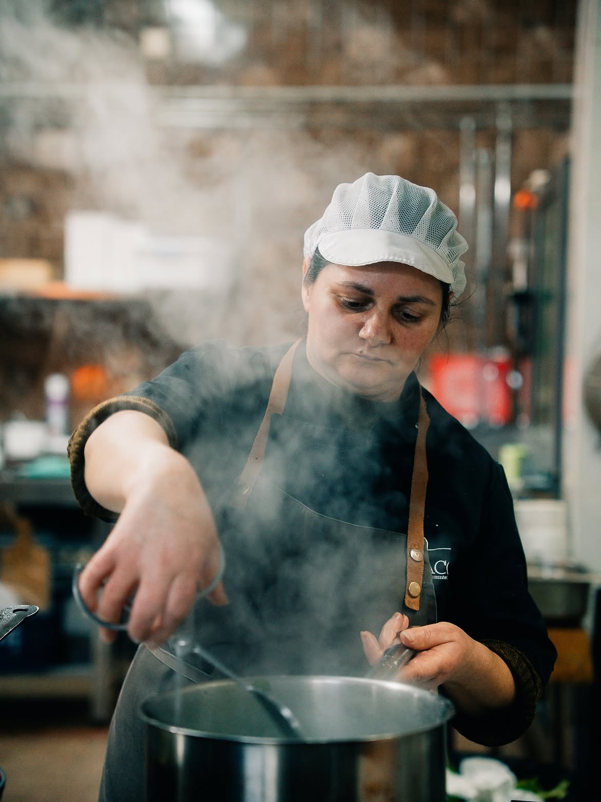 Cozinheira mexendo uma panela fumegante na cozinha
