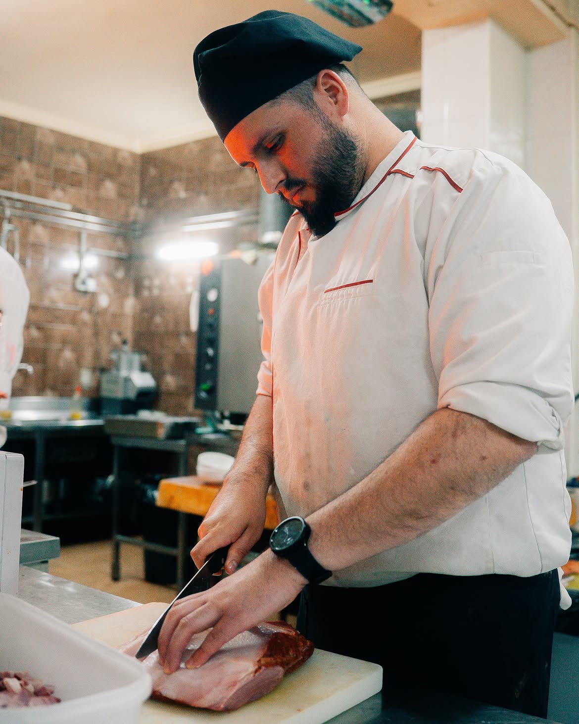 Cozinheiro fatiando presunto na cozinha do Dom Baco